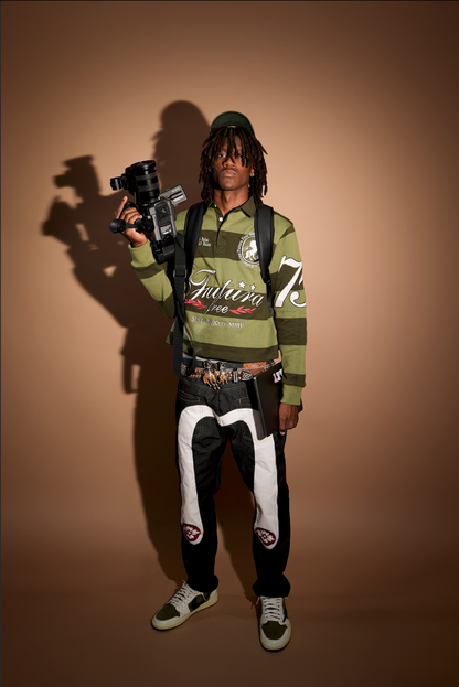 Person holding a camera against a brown background in streetwear clothing
